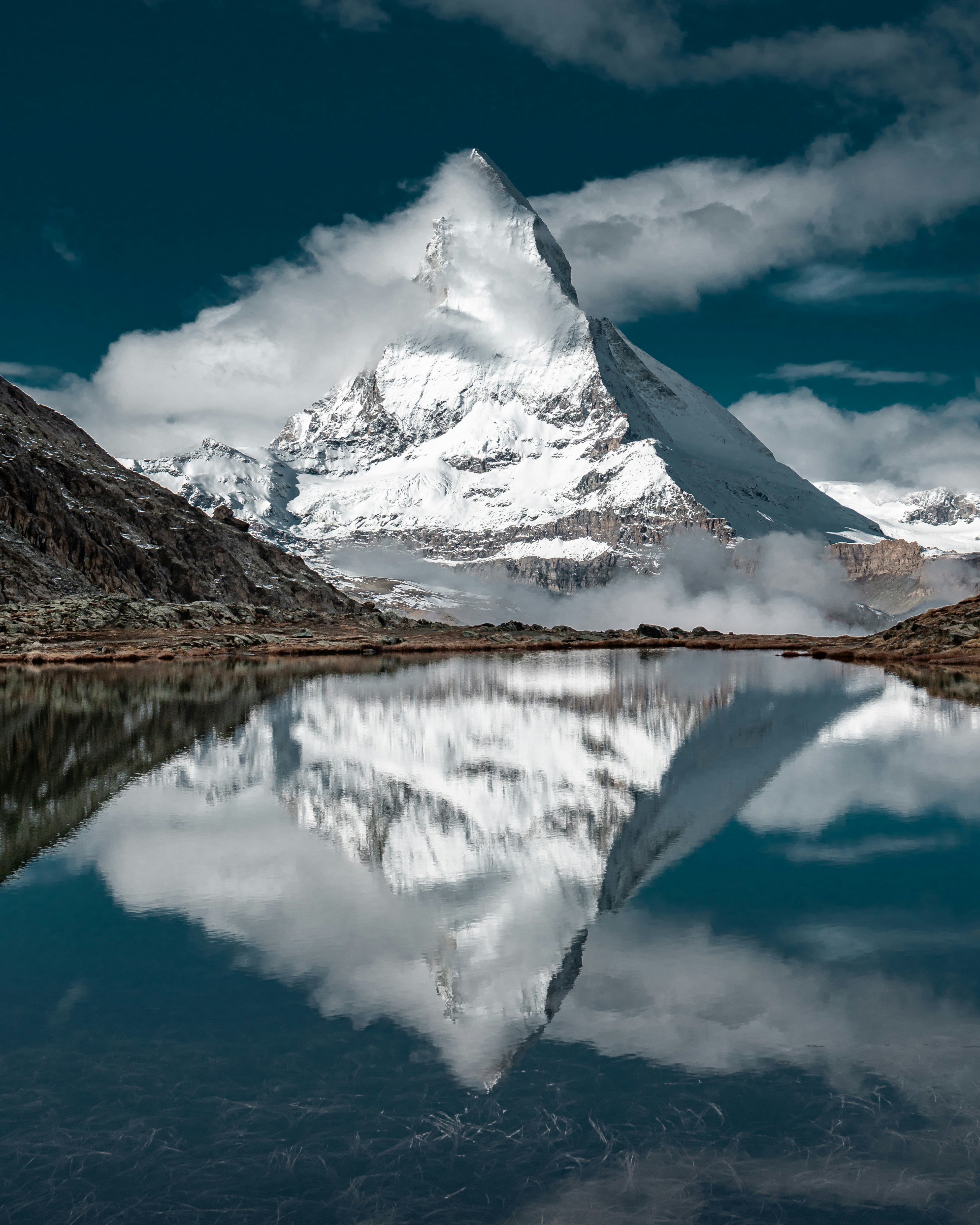 snow covered mountain near lake under blue sky during daytime